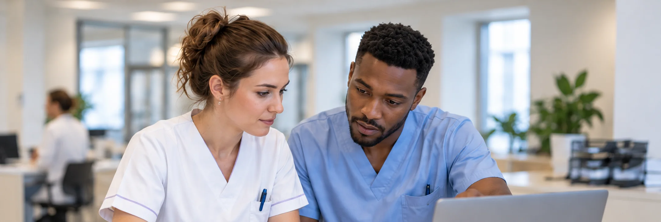 Zwei Pflegefachpersonen besprechen sich an einem Arbeitsplatz im Personalraum
